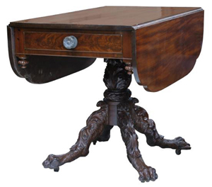 This Empire drop-leaf table, circa 8130, has as solid mahogany top and base with crotch cut mahogany veneer on the drawer front and skirt.
